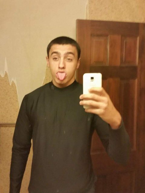 A young man takes a playful mirror selfie while sticking out his tongue.