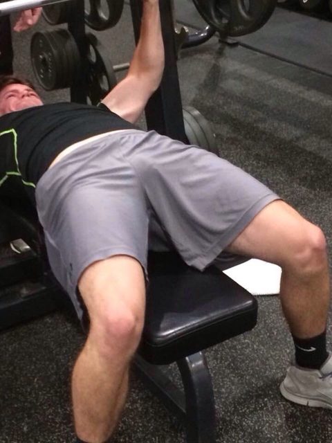 A man works out on a bench press in a gym.