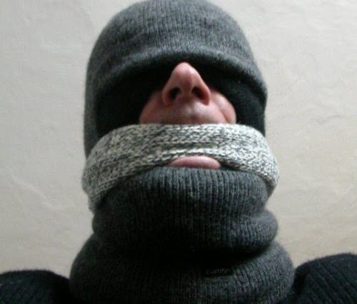 A man wears multiple grey knit items covering most of his face.