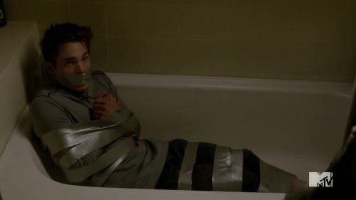 A young man is restrained with duct tape in a bathtub.