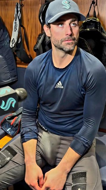 A man in sportswear and a cap sits in a locker room.