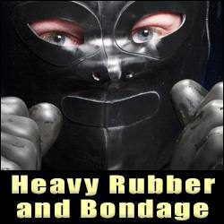 A close-up view of a person wearing a heavy black rubber hood and rubber gloves staring into the camera.