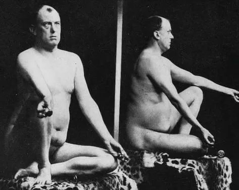 A vintage black-and-white studio photograph depicting front and profile views of a nude mature man seated on a leopard-print covered platform.