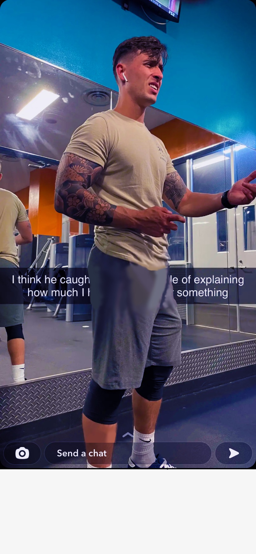 A muscular man in sportswear stands in a gym, appearing to explain something.