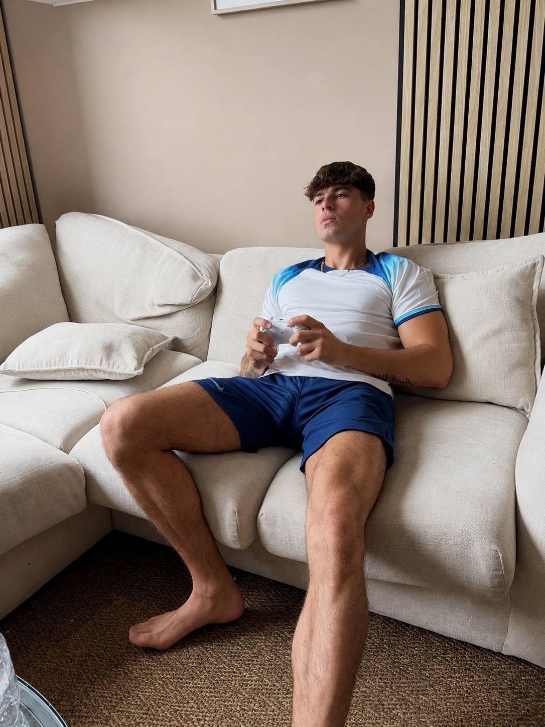 A young man sits on a couch playing a video game.